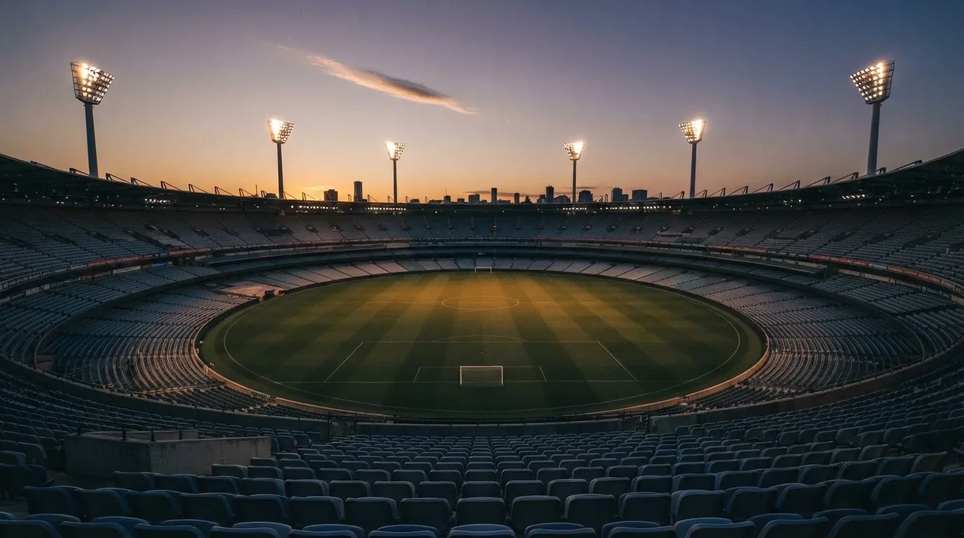 An empty football stadium with floodlight masts at dusk