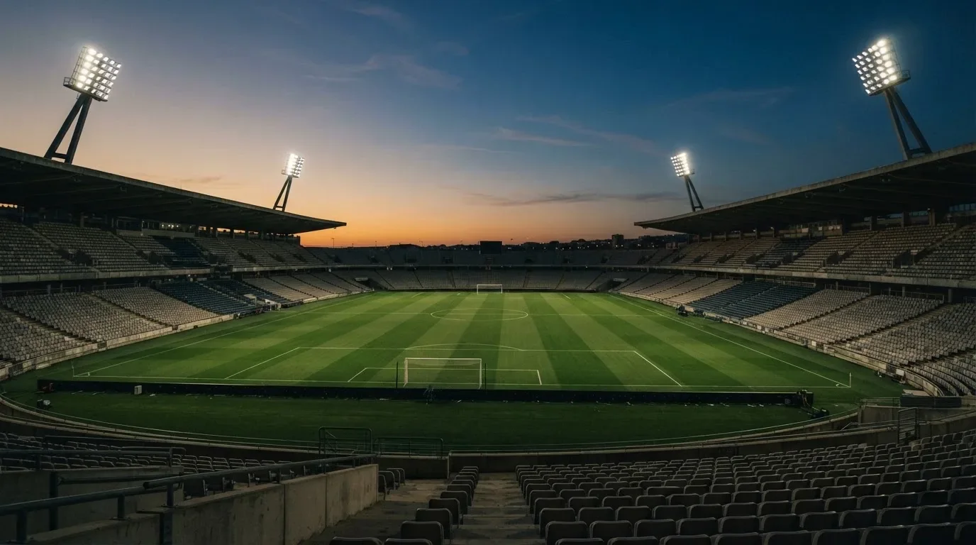 An empty football stadium with floodlight masts at dusk