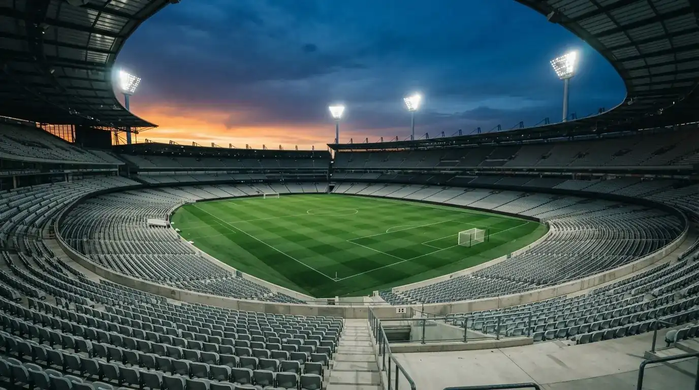 An empty football stadium with floodlight masts at dusk