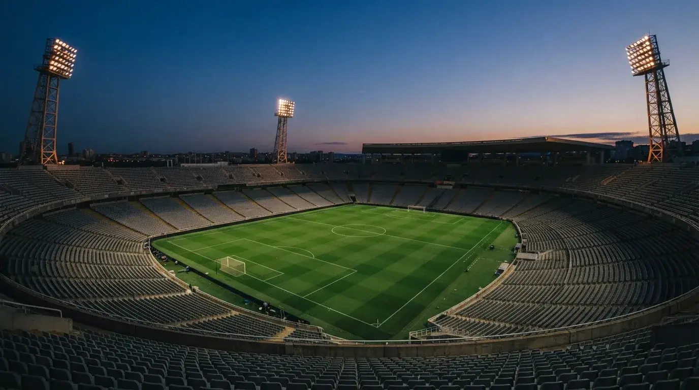 An empty football stadium with floodlight masts at dusk