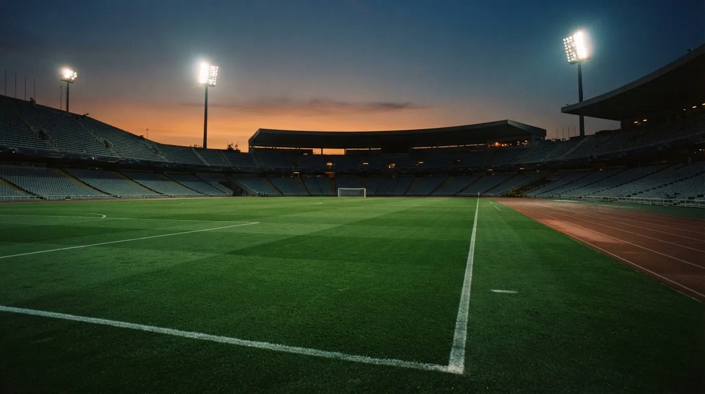 An empty football stadium with floodlight masts at dusk