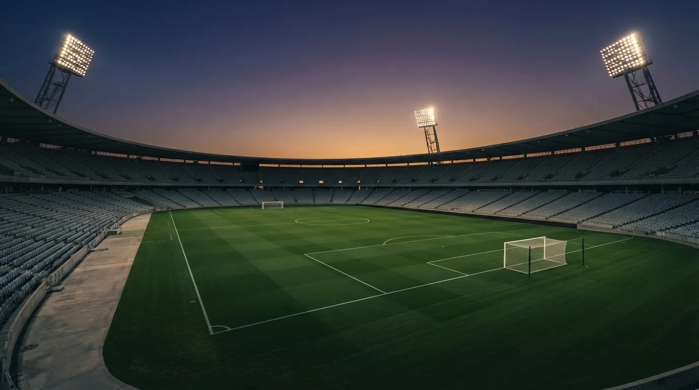 An empty football stadium with floodlight masts at dusk
