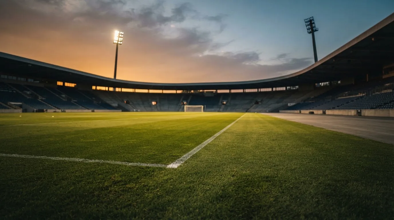 An empty football stadium with floodlight masts at dusk