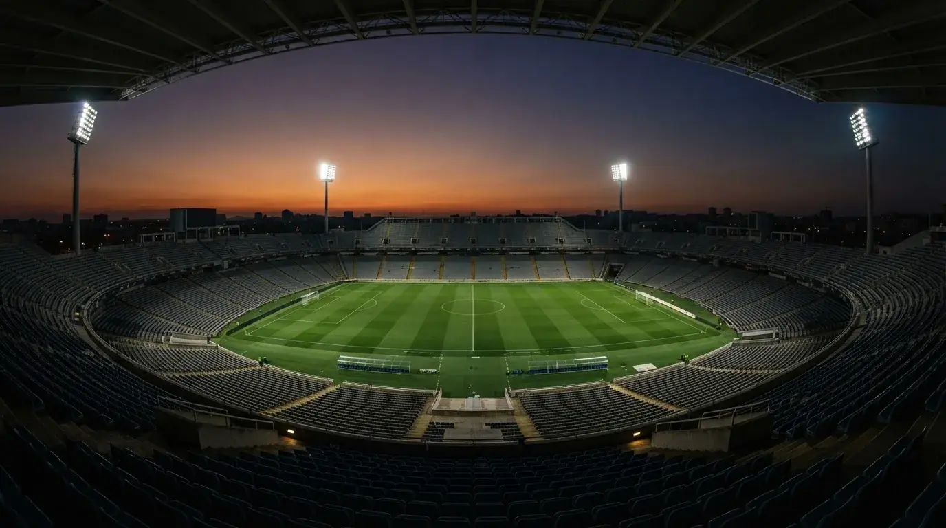 An empty football stadium with floodlight masts at dusk