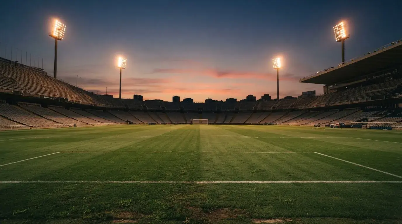 An empty football stadium with floodlight masts at dusk