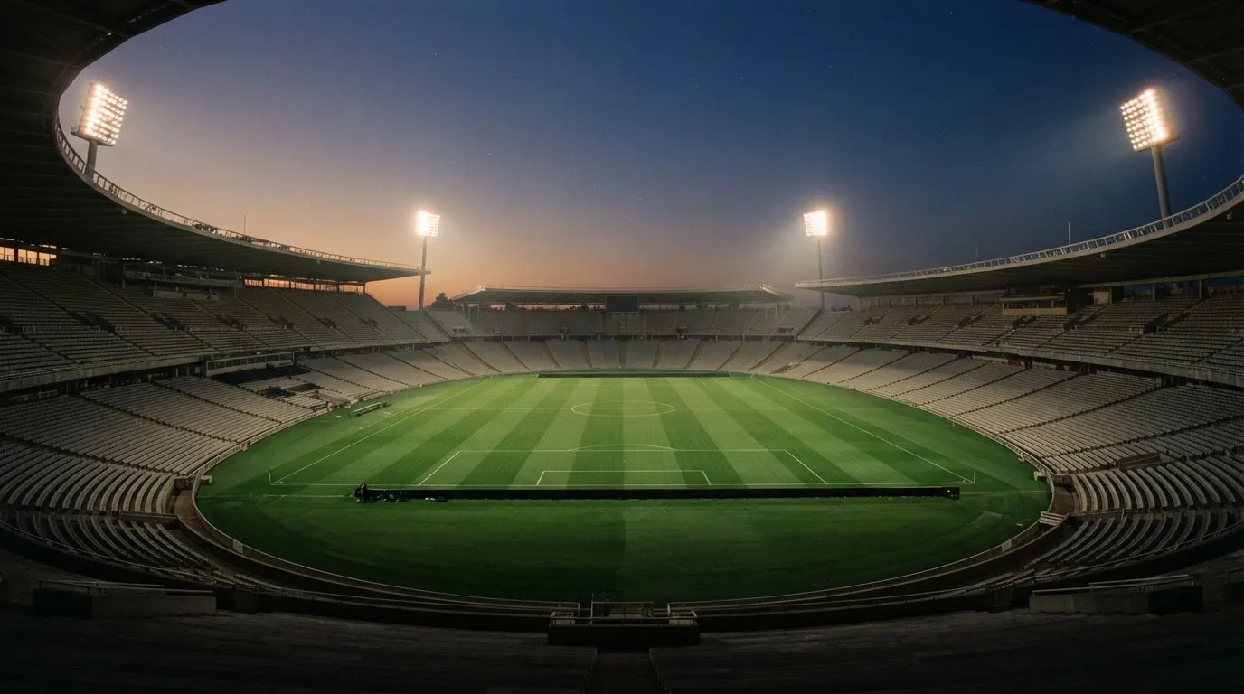 An empty football stadium with floodlight masts at dusk
