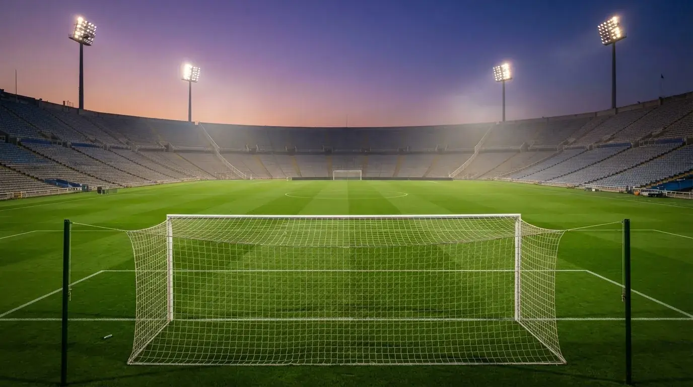 An empty football stadium with floodlight masts at dusk