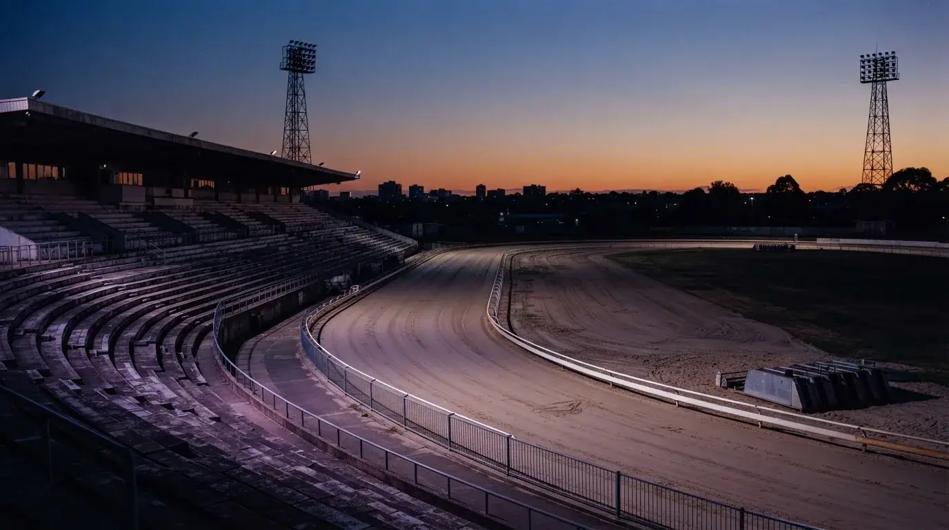 An empty football stadium with floodlight masts at dusk