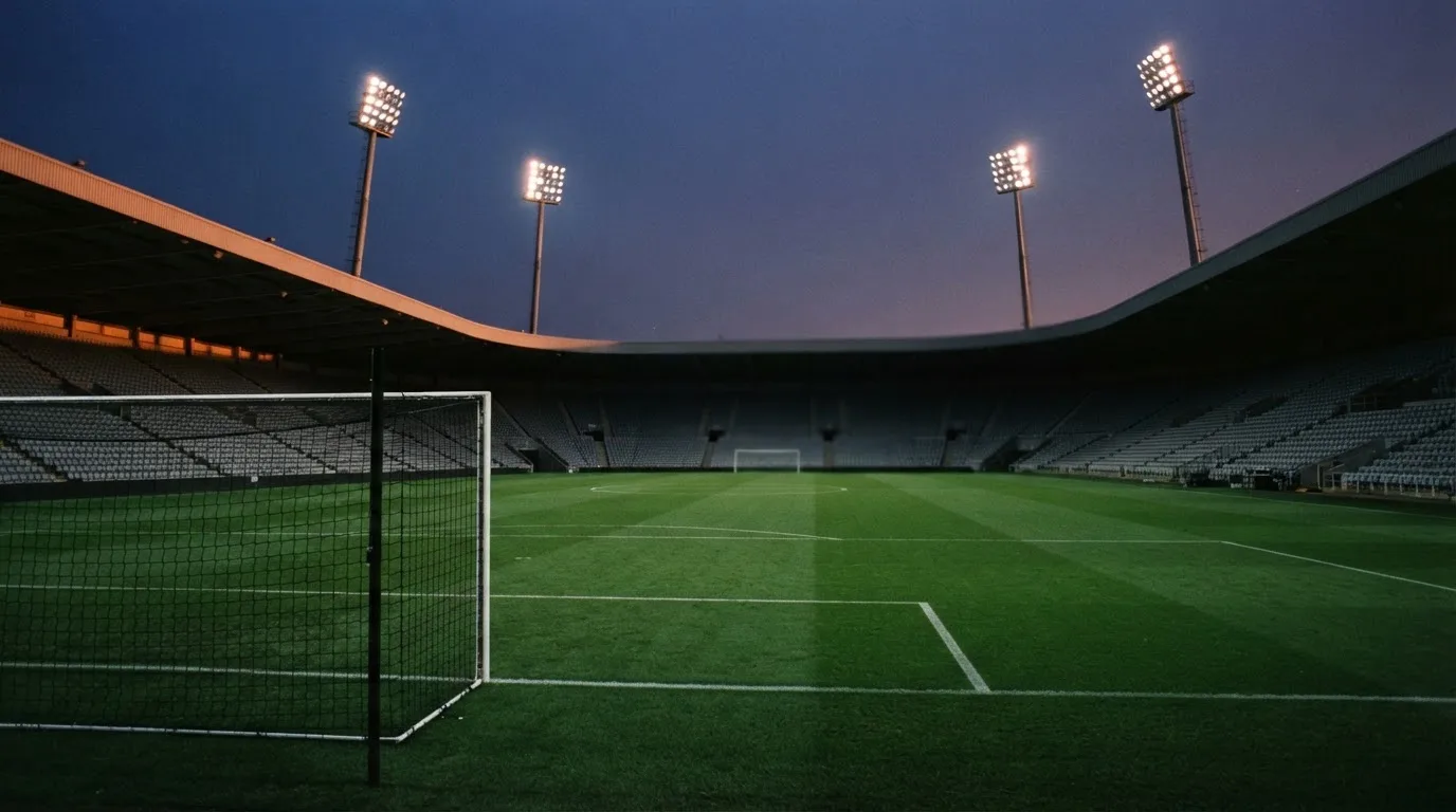 An empty football stadium with floodlight masts at dusk