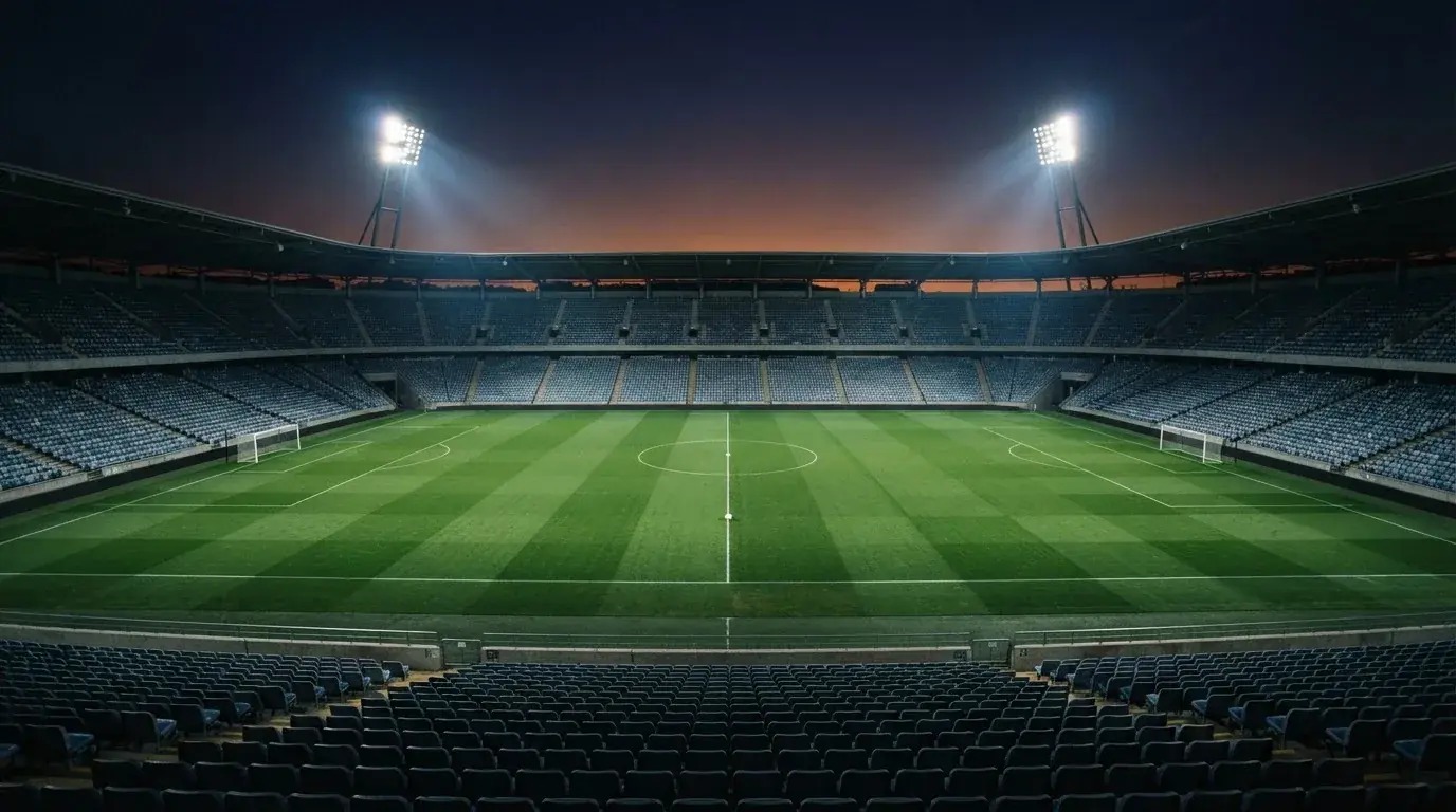 An empty football stadium with floodlight masts at dusk