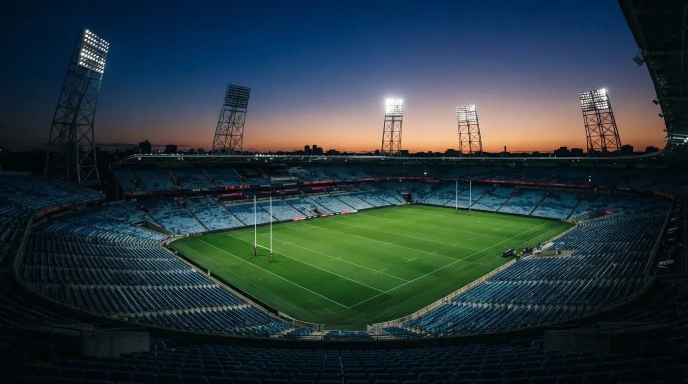 An empty football stadium with floodlight masts at dusk