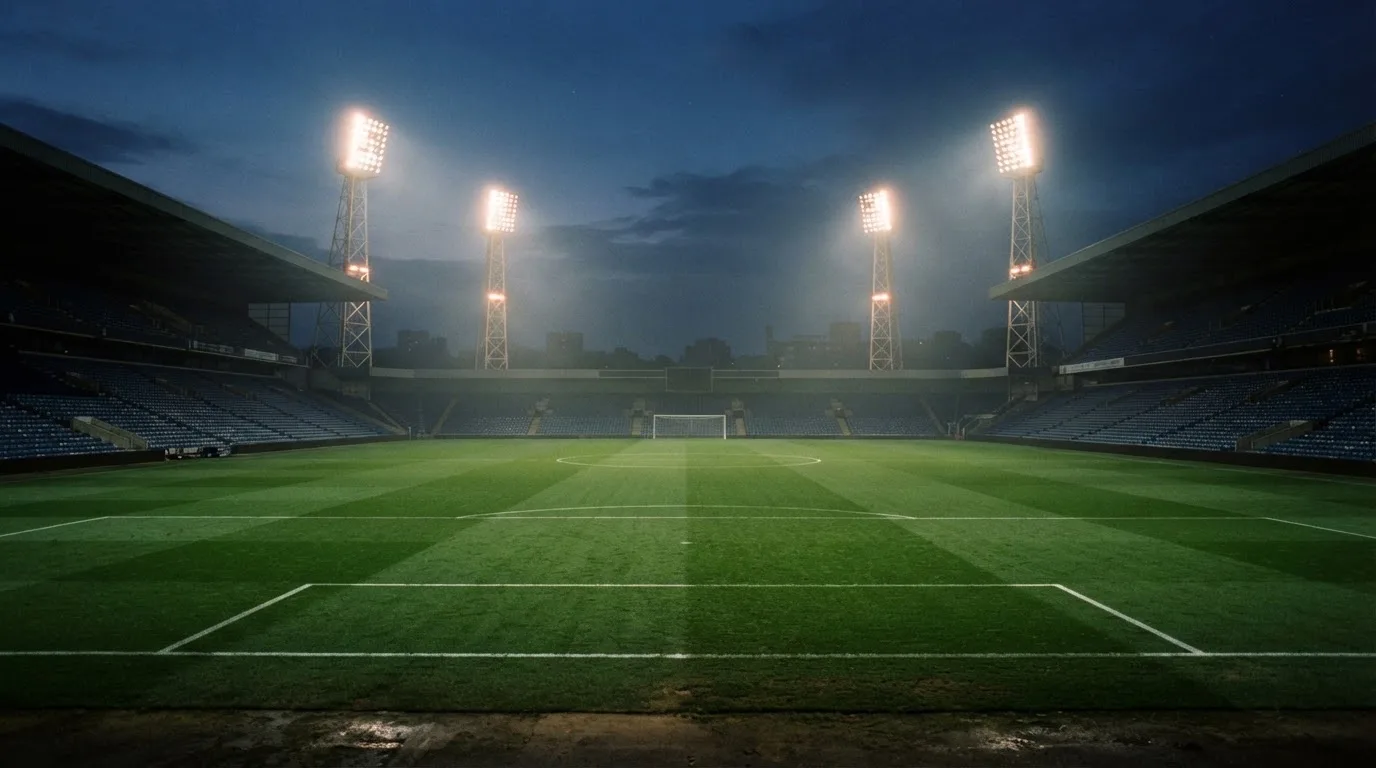 An empty football stadium with floodlight masts at dusk