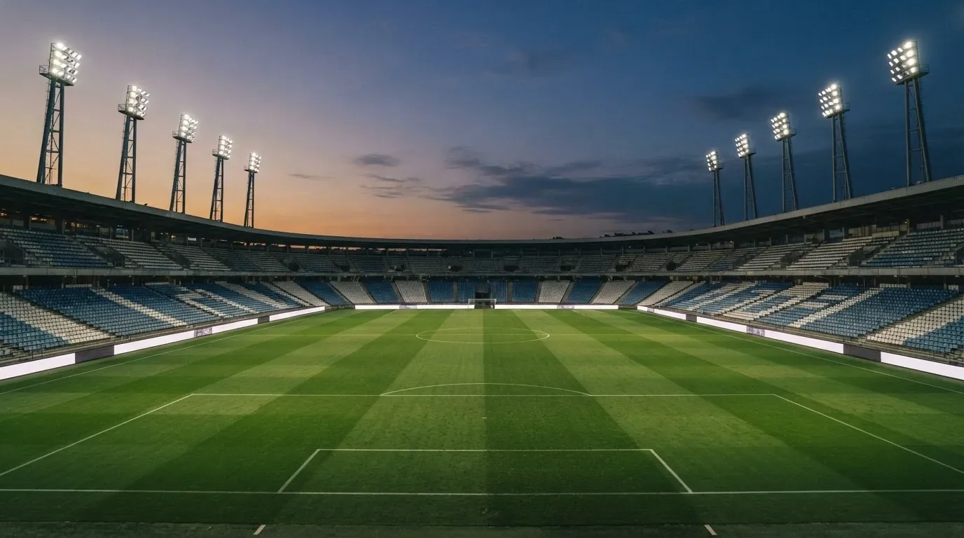 An empty football stadium with floodlight masts at dusk